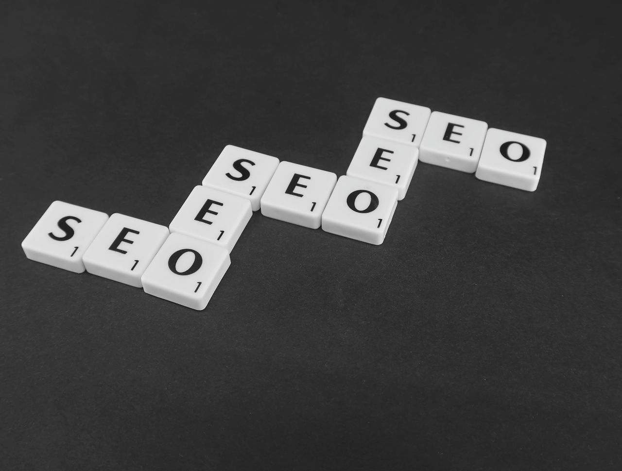 services-01 SEO spelled with Scrabble tiles on a black surface, representing search engine optimization concepts.